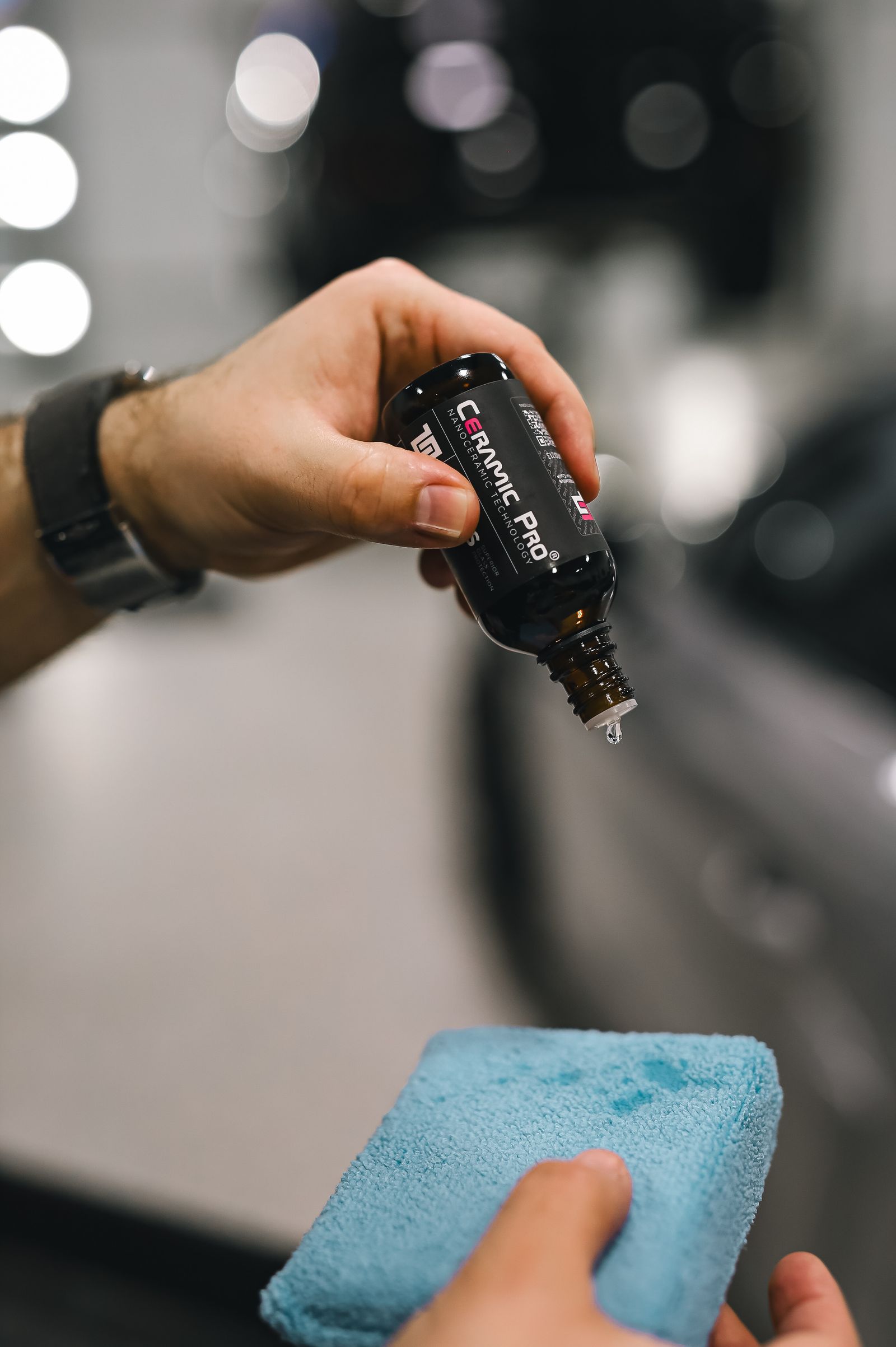 Detailer's hands applying ceramic coating to a panel with an applicator sponge